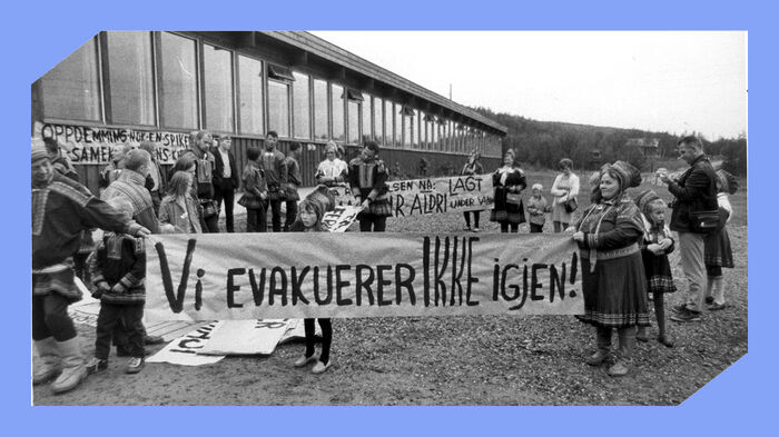 Svarthvit foto av kvinner, menn og barn i samisk drakt med bannere der det st?r "Vi evakuerer ikke igjen!".