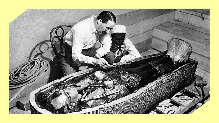 To menn sitter b?yd over en egyptisk mumie og studerer den n?ye. Foto. 
