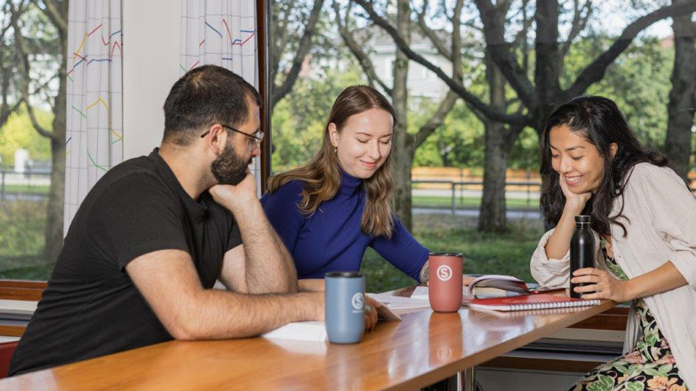 Studenter som snakker sammen rundt et bord på Det humanistiske fakultet, UiO.