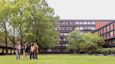 Students in a garden in the summer, building in the background. Photo