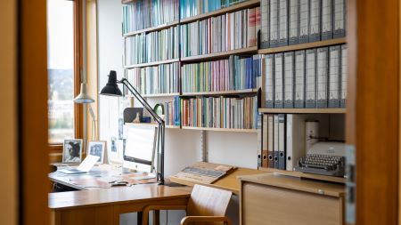 Et ryddig kontor med bokhyller og skrivebord. Foto