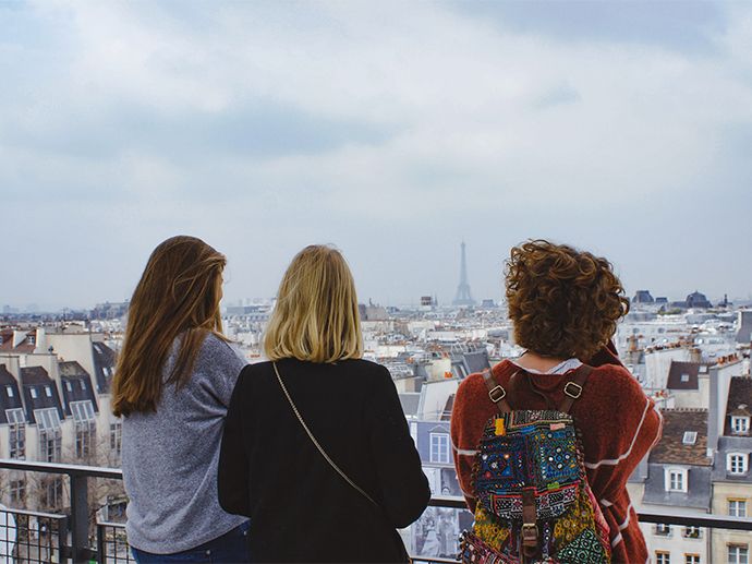Tre mennesker står og ser utover byen Paris. Eiffeltårnet kan skimtes i det fjerne. Foto