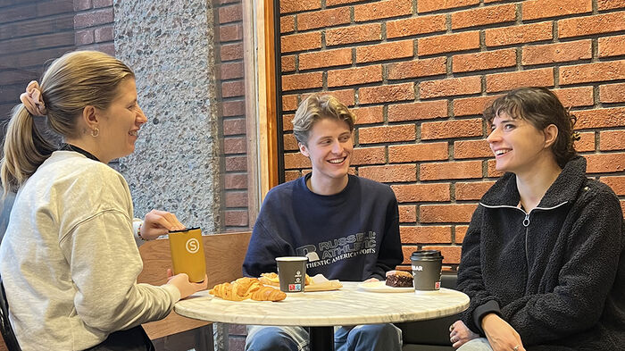 Tre personer som snakker sammen over et bord