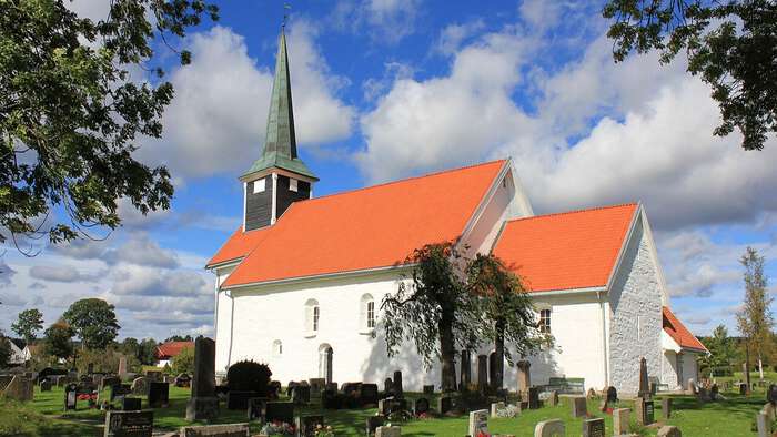 hvit kirke med kirkegård rundt om sommeren