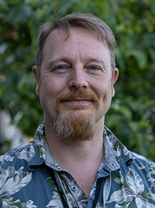 Portrettfoto, mann, smil, skjegg og bart, kort brunt kort hår, blå og hvit skjorte