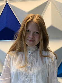 Portrettfoto, kvinne, smilende, langt hår, midtskill, hvit blondebluse