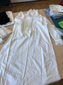 Hvit brodert kjole ligger på et bord.